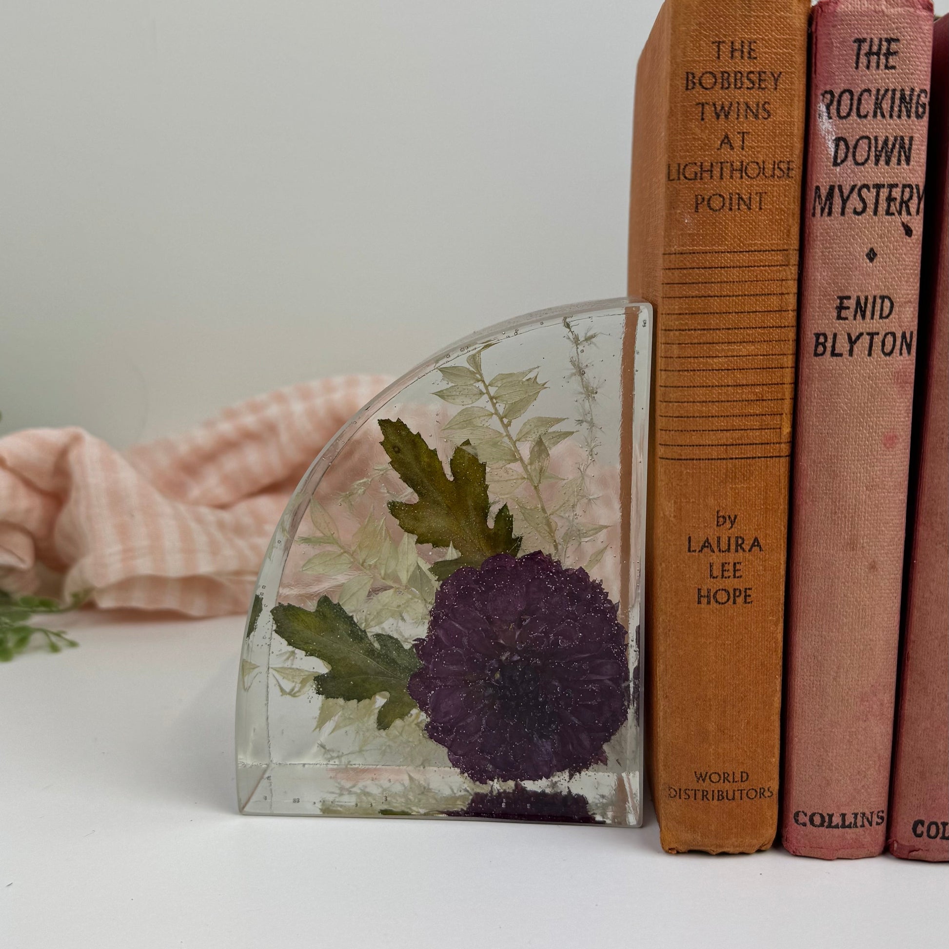Decorative bookend with floral design next to vintage books on a white surface.